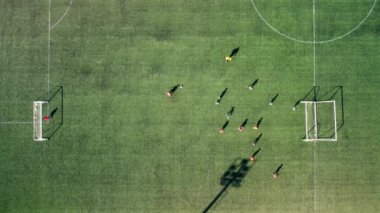 Futbol sahasında futbol oynayan çocukların hava görüntülerini çeken bir dronun üst görüntüsü.