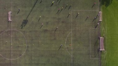 Futbol sahasında futbol oynayan çocukların hava görüntülerini çeken bir dronun üst görüntüsü.