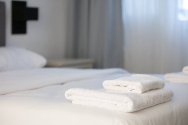 Beyaz temiz havlular otel yatağın üstüne yığılmış