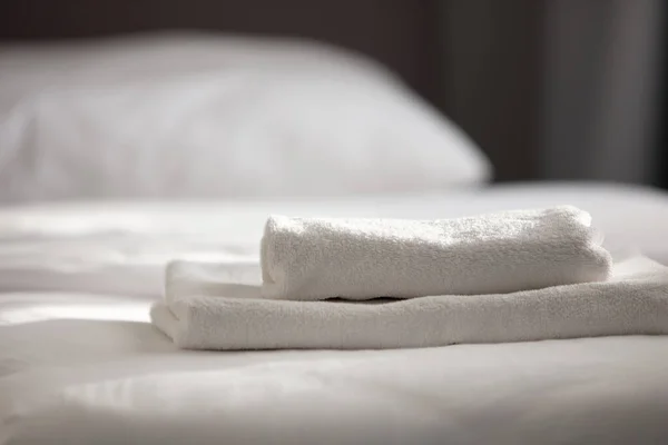 Beyaz temiz havlular otel yatağın üstüne yığılmış — Stok fotoğraf