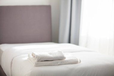 Beyaz temiz havlular otel yatağın üstüne yığılmış