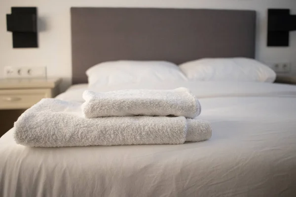 Toalhas limpas brancas empilhadas na cama do hotel — Fotografia de Stock