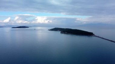 Denizde bir ada. Sakin mavi denizin ortasındaki yeşil tropikal adanın harika drone görüntüsü 