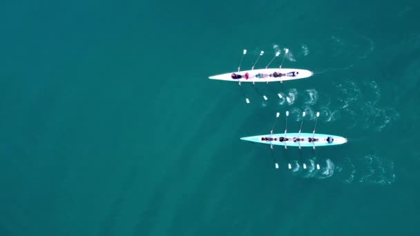 Drohnenvideo aus der Vogelperspektive von zwei Sportkanus, die von einem Team junger Männer und Frauen betrieben werden 