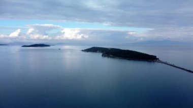 Denizde bir ada. Sakin mavi denizin ortasındaki yeşil tropikal adanın harika drone görüntüsü 