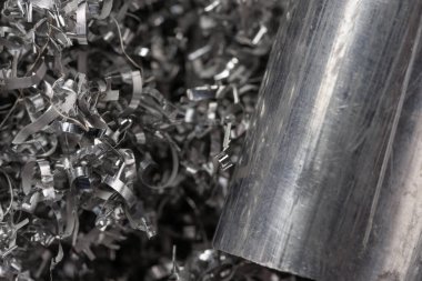 Gülen makinenin talaşı üzerinde alüminyum bilye. Endüstriyel yakın çekim fotoğrafı. Girdap alüminyum talaşlar üzerinde iki metal çubuğun yan görüntüsü. Endüstriyel teknoloji atölyesi. Yakın çekim görünümü.