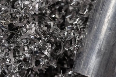 Gülen makinenin talaşı üzerinde alüminyum bilye. Endüstriyel yakın çekim fotoğrafı. Girdap alüminyum talaşlar üzerinde iki metal çubuğun yan görüntüsü. Endüstriyel teknoloji atölyesi. Yakın çekim görünümü.