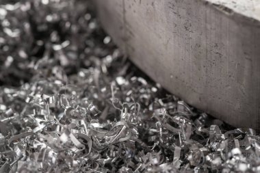 Gülen makinenin talaşı üzerinde büyük magnezyum çubuğu. Makro atış. Üst görünüm endüstriyel yakın çekim fotoğrafı. Girdap magnezyum talaşlarının üzerindeki metal çıkıntının fotoğrafı. Endüstriyel teknoloji atölyesi. Teknoloji konsepti geçmişi.