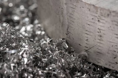 Gülen makinenin talaşı üzerinde büyük magnezyum çubuğu. Makro atış. Üst görünüm endüstriyel yakın çekim fotoğrafı. Girdap magnezyum talaşlarının üzerindeki metal çıkıntının fotoğrafı. Endüstriyel teknoloji atölyesi. Teknoloji konsepti geçmişi.
