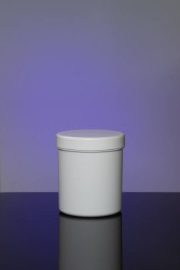 White cosmetic jar mokup with reflection on purple violet background, spot light on background, beauty care concept