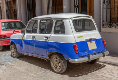 İki renkli klasik Avrupalı eski araba, bir kasabada bir caddeye park edilmiş.