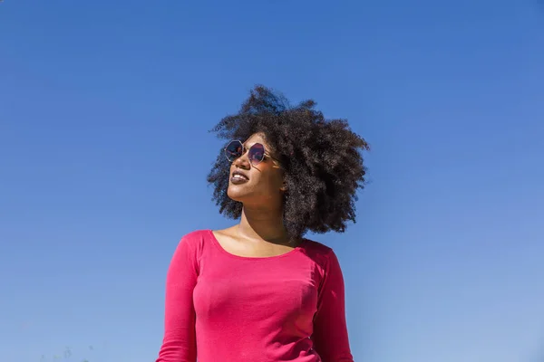 Attractive woman with sunglasses walks on a lovely sunny summer day with a blue sky in the background