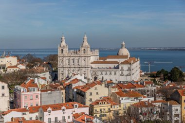 Tipik bir Lizbon kilisesi manzarası ve arka planda deniz olan klasik evler.