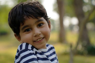 Dört yaşındaki Güney Asyalı Pakistanlı çocuk açık havada mutlu bir ruh hali içinde.