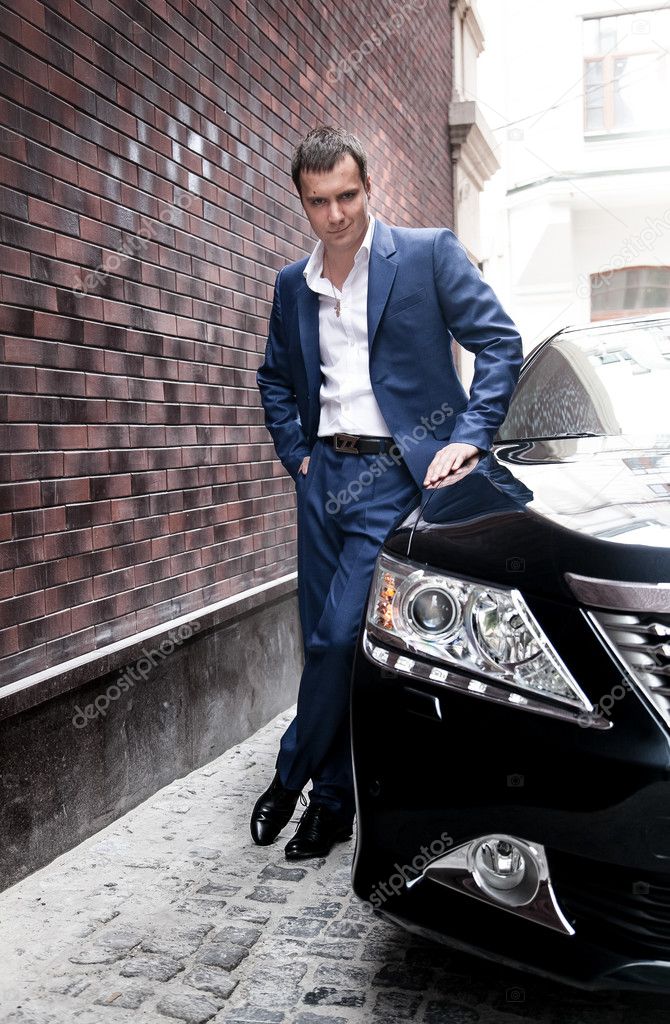 Man in suit posing near car