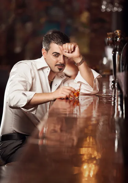Homem de camisa branca sentado perto de bar mesa com uísque — Fotografia de Stock