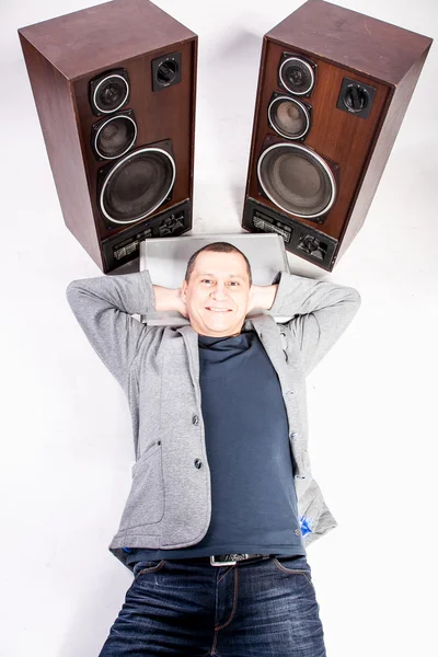 Mann liegt auf dem Boden neben zwei großen Lautsprechern — Stockfoto