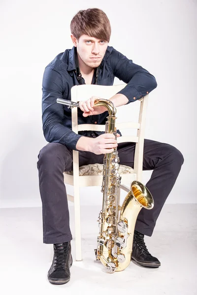 Musician sitting on chair and holding saxophone — Stock Photo, Image