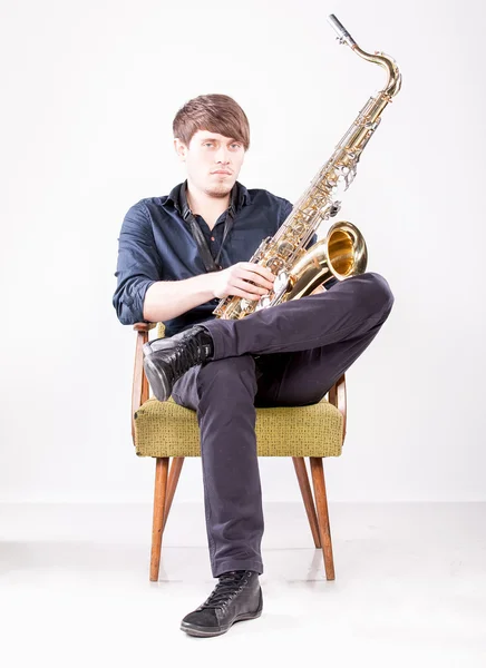 Saxophonist posing on chair — Stock Photo, Image