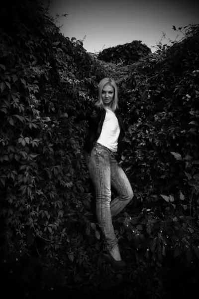 Mujer posando cerca de la pared cubierta de plantas —  Fotos de Stock