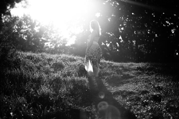 Black and white photo of beautiful girl walking in sun rays