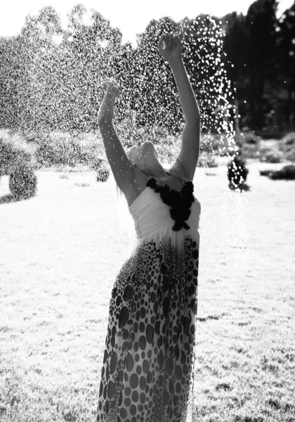 Menina de pé no gramado sob gotas de água — Fotografia de Stock