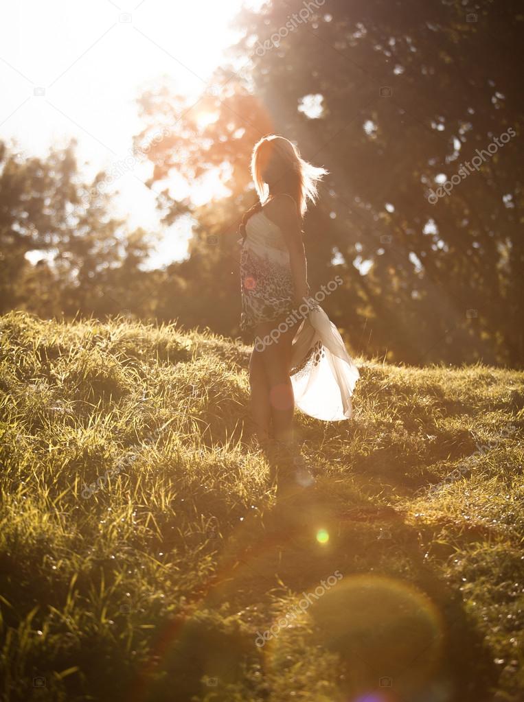 Girl walking in park in sun rays