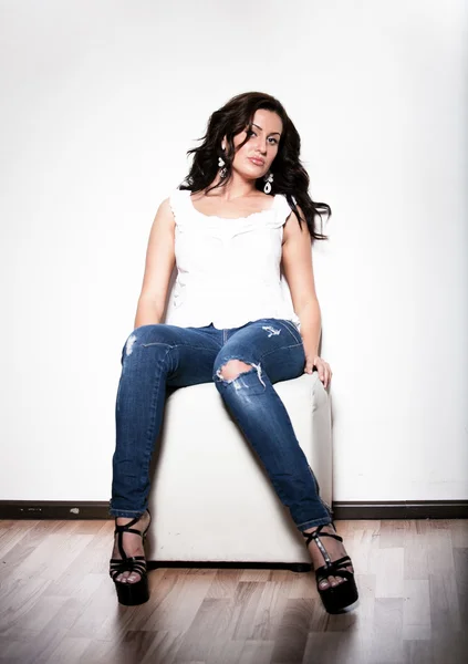 Girl in jeans and white singlet sitting on chair — Stock Photo, Image