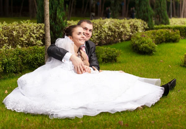 Paar sitzt auf Gras im Park und umarmt sich — Stockfoto