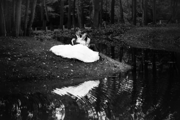 Семейная пара, сидящая на берегу реки — стоковое фото