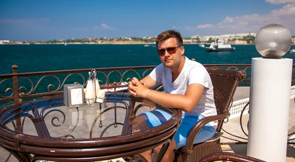 Hombre con gafas de sol sentado en la terraza en la cafetería — Foto de Stock