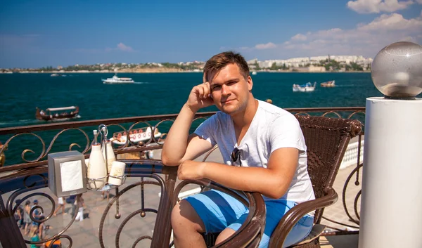 Hombre sentado en la cafetería cerca del mar — Foto de Stock