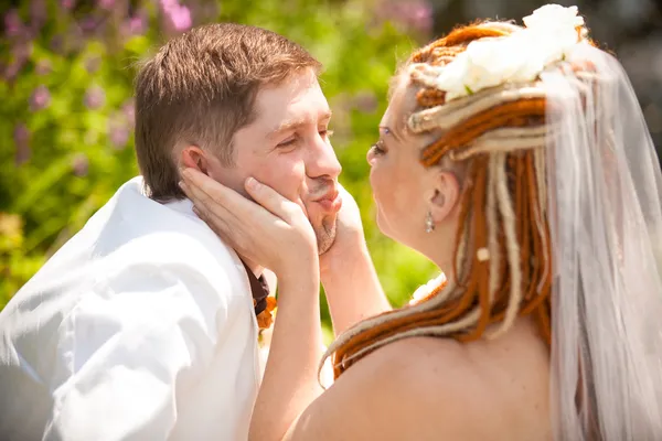Bride with red dreadlocks touching grooms cheeks — Stock Photo, Image