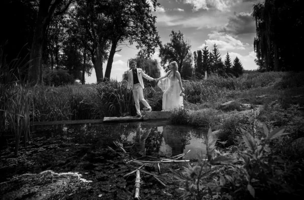 Casal recém-casado andando na ponte perto do lago — Fotografia de Stock