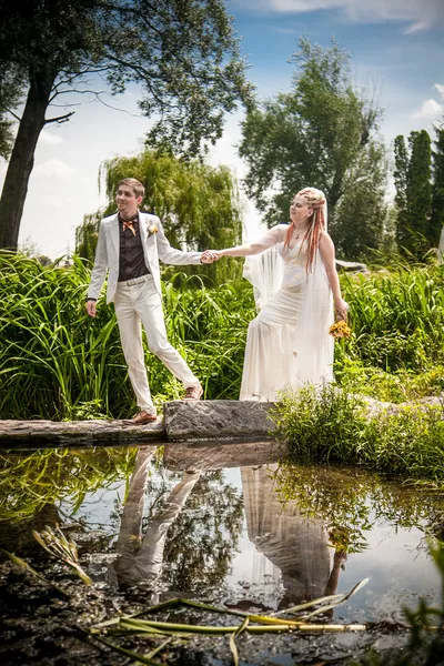 Novio sosteniendo las manos de las novias y caminando en puente — Foto de Stock