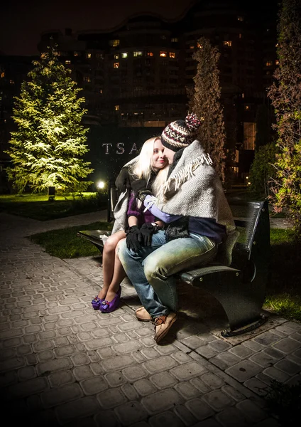 Couple in love sitting on bench covering with plaid — Stock Photo, Image