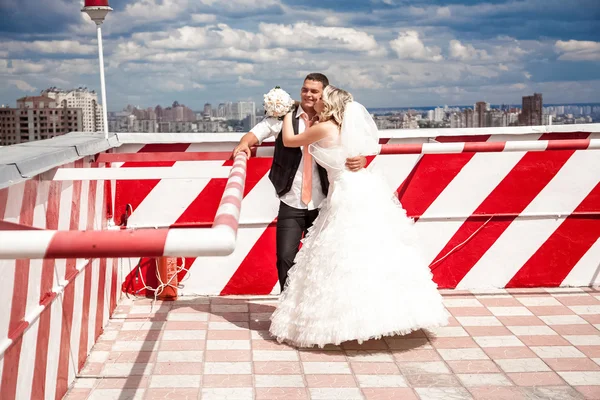 Bride and groom hugging in heliport against city view — Stock Photo, Image