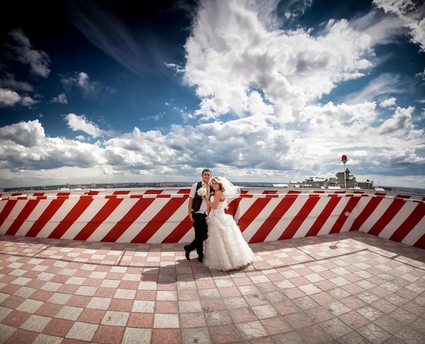 Coppia sposata in piedi sul tetto contro cielo blu — Foto Stock