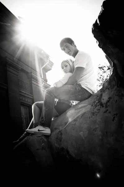 Young couple sitting on ancient monument in sunlight — Stock Photo, Image