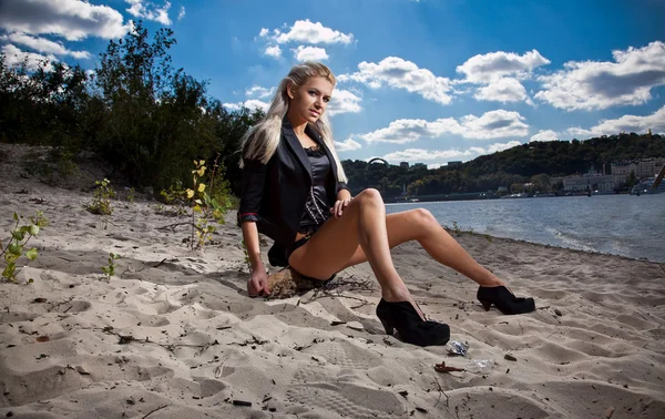 Menina loira sexy sentada na costa — Fotografia de Stock