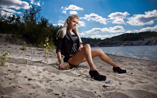 Sexy blonde girl sitting on shore — Stock Photo, Image