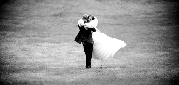 Foto do noivo levantando noiva e girando-a — Fotografia de Stock