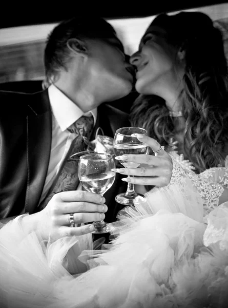 Casal casal beijando no carro enquanto segurando copos de champanhe — Fotografia de Stock