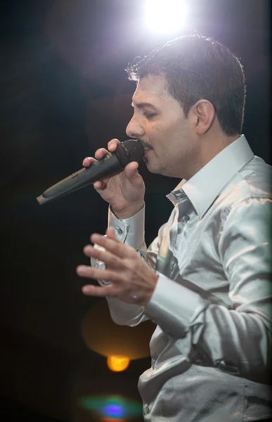 Handsome man singing on stage against spot light — Stock Photo, Image