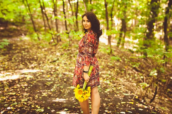 Fille en robe tenant tas de tournesols dans la forêt — Photo