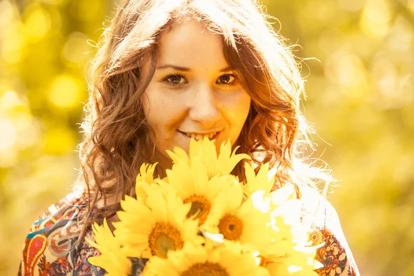Porträtt av flicka med solrosor poserar i solstrålarna — Stockfoto