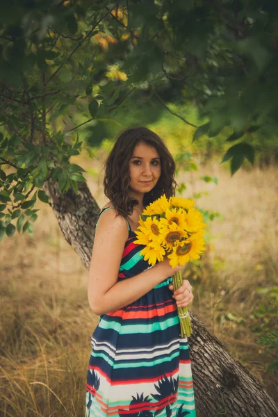 Mooie jonge vrouw met zonnebloemen in park — Stockfoto