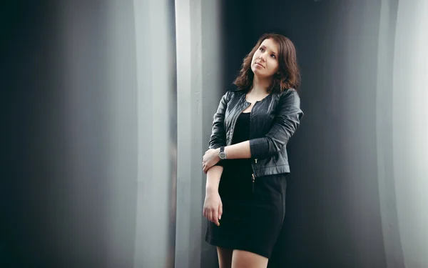 Woman in black leather coat posing against city — Stock Photo, Image