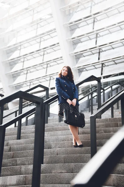 Woman standing on big stairs outdoor and leaning against railings — Stock Photo, Image