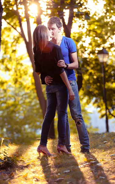 Jong koppel knuffelen in park in zonnestralen — Stockfoto